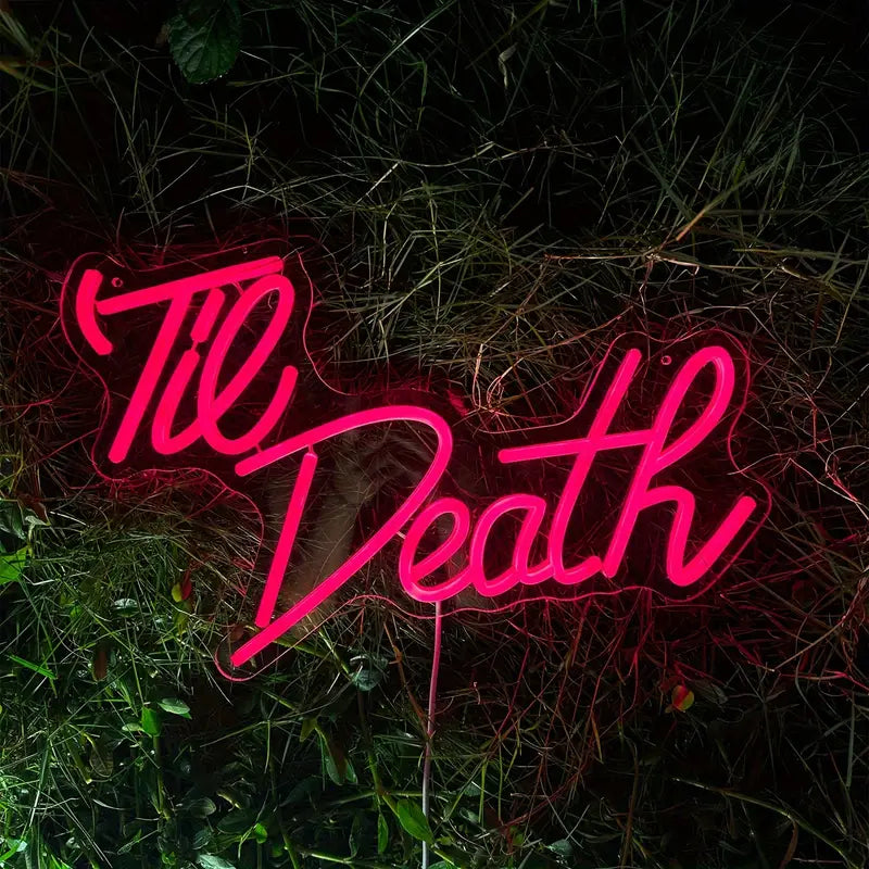 Pink neon Til Death sign in grass