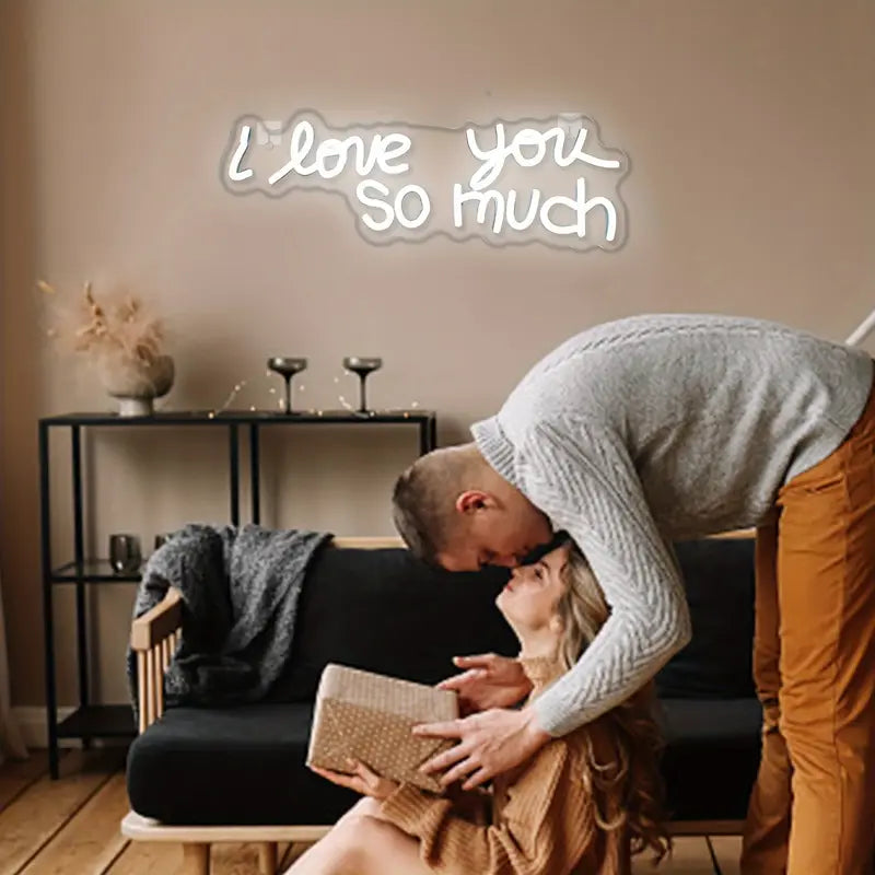Couple sharing a tender moment with I love you so much neon sign