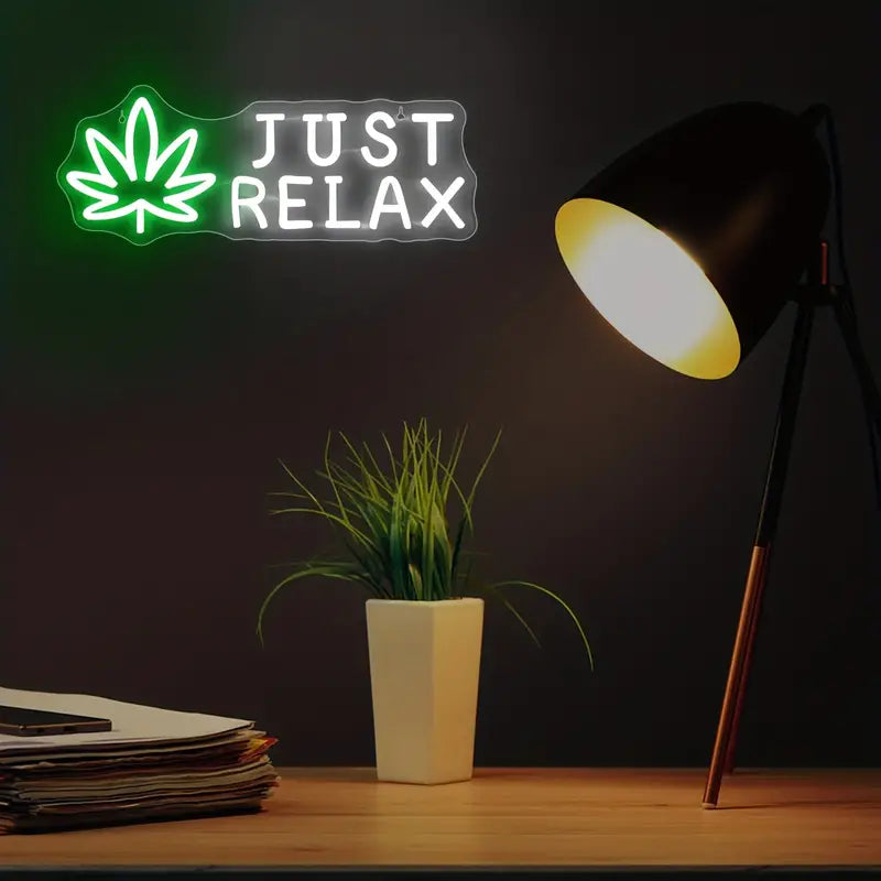 Neon sign 'Just Relax' with leaf, desk lamp, potted plant