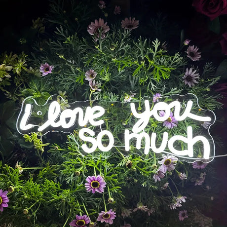Neon sign with the words I love you so much surrounded by flowers
