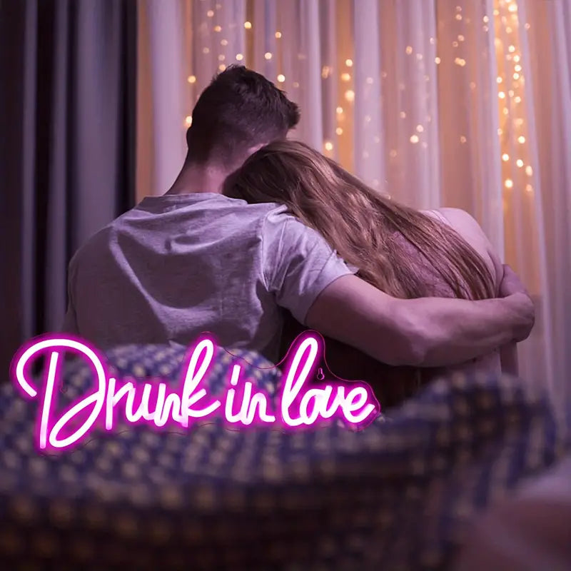 Couple hugging with 'Drunk in Love' neon light.