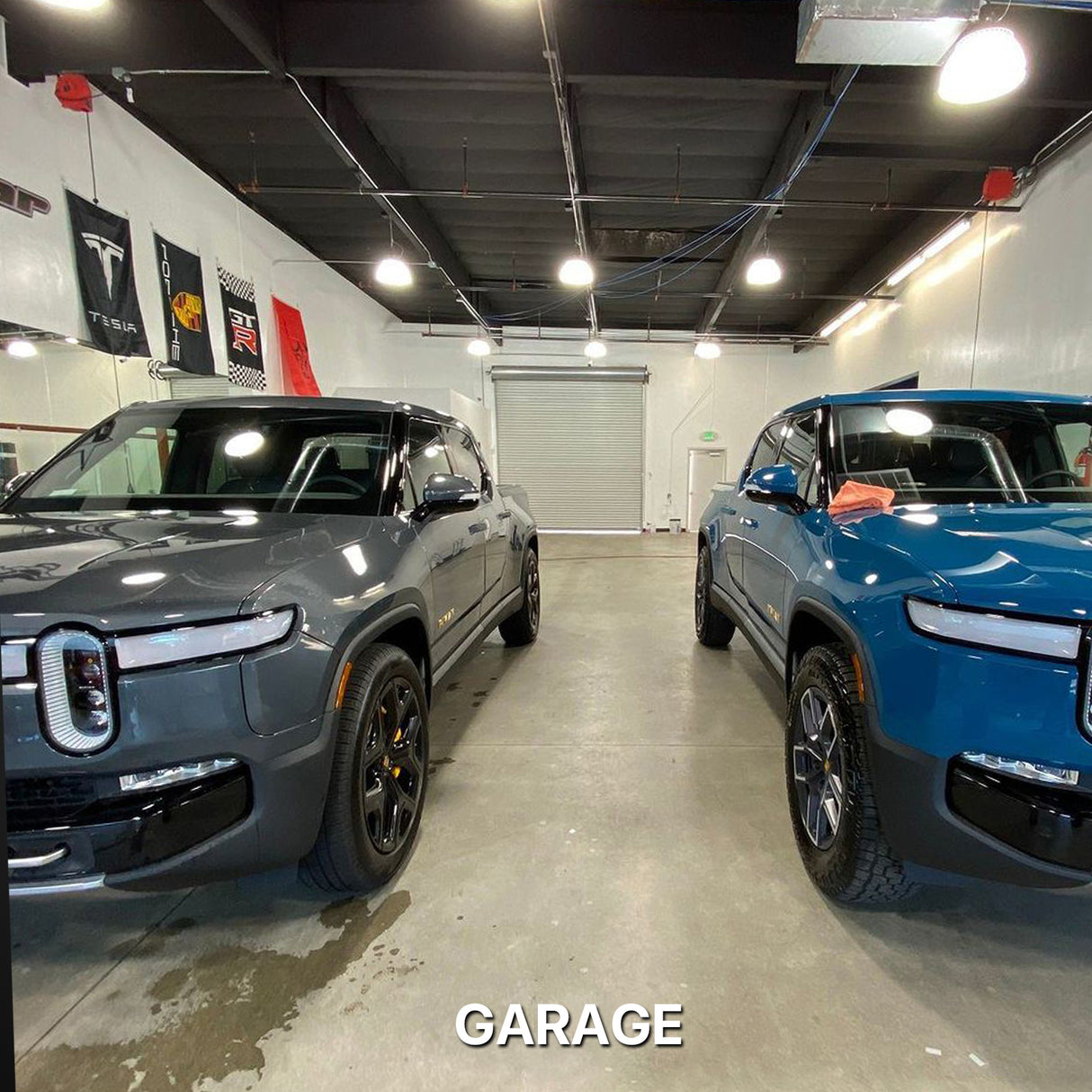 Two pickup trucks in a garage with high bay lights