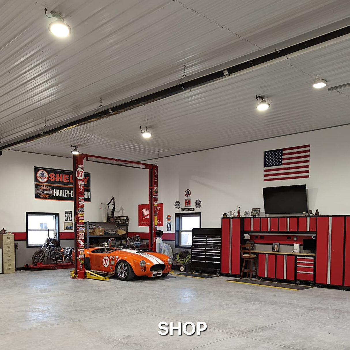 Shop with high bay lights, orange sports car and Harley-Davidson