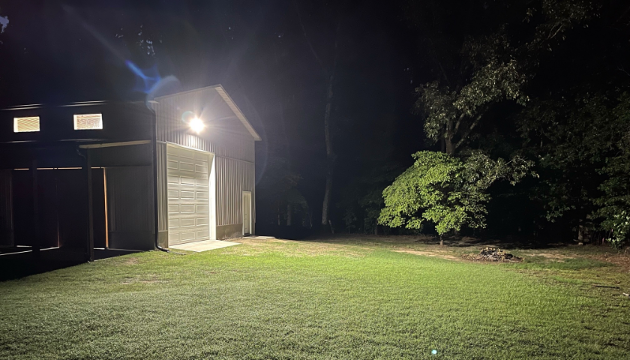 led flood lights lighting up the front of yard of pole barn