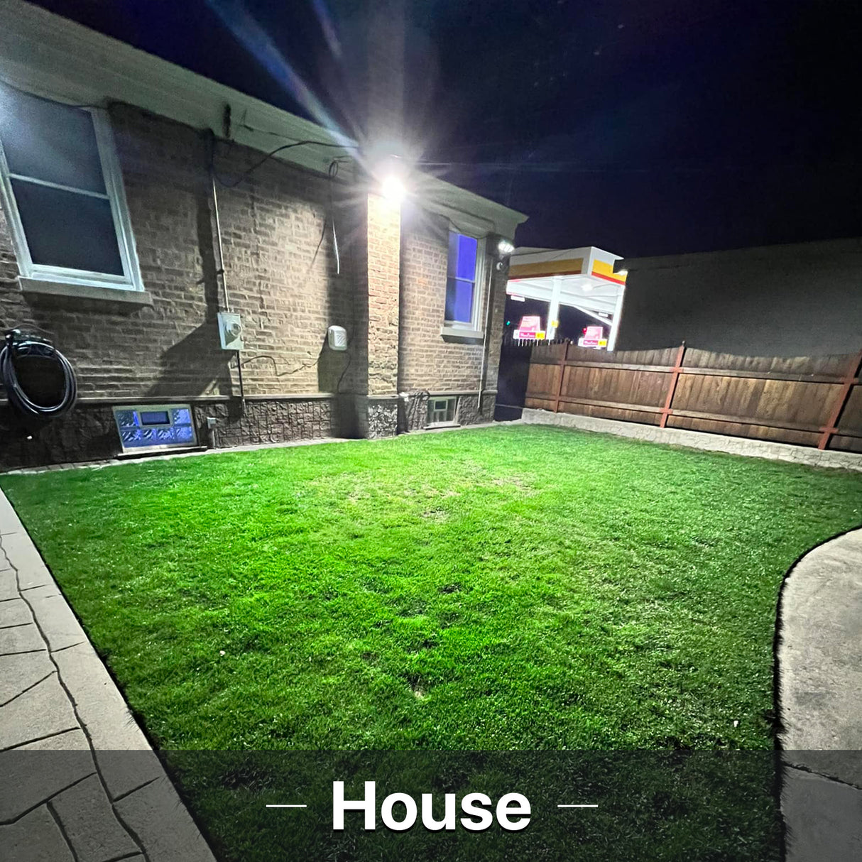 Hyperlite Wall Pack Light illuminating a house and yard at night