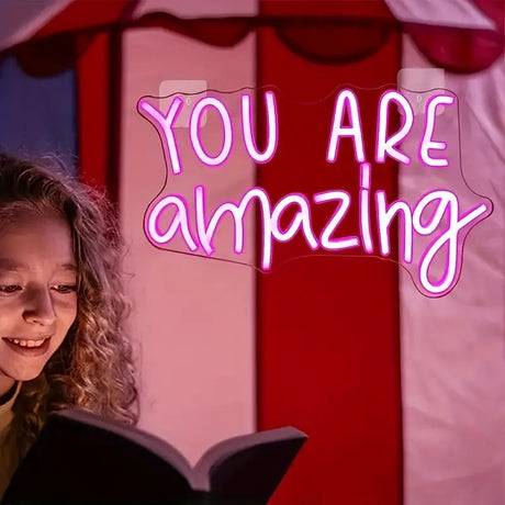 Girl reading book with You Are Amazing neon sign light