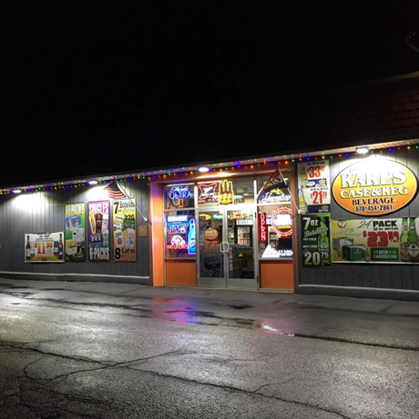 A liquor store lit up hyperlite flood lights at night.