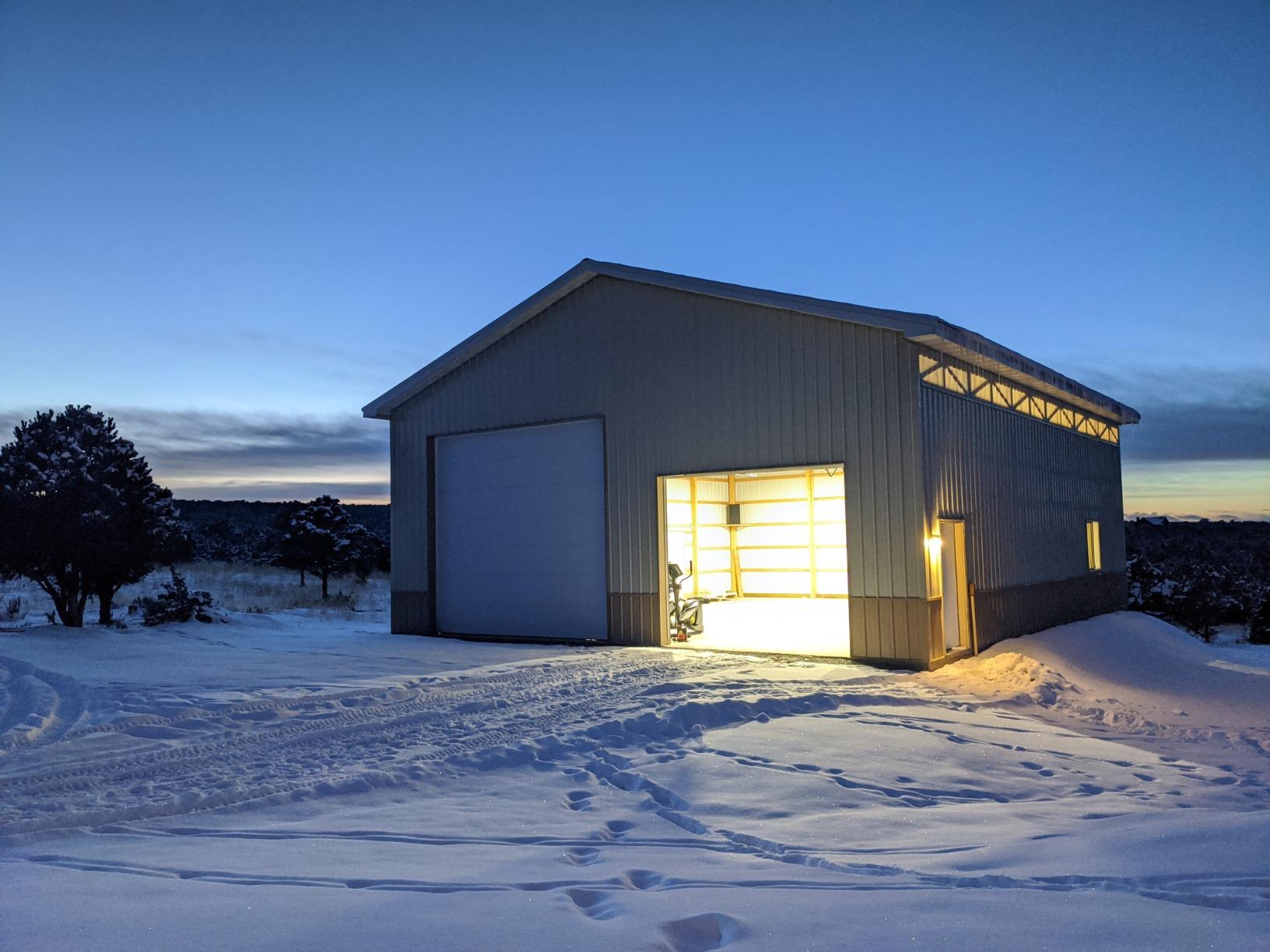 A snowy barn at dusk, illuminated by warm LED Lights from within, casting a cozy glow.
