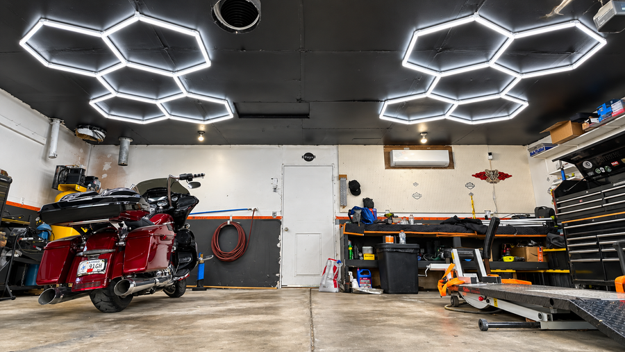Garage with hexagonal LED ceiling lights, parked motorcycle, and workbench.