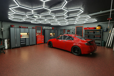 A sleek, modern garage with a red sports car, distinctive hexagonal LED lighting on the ceiling, and matching gray and red storage cabinets.