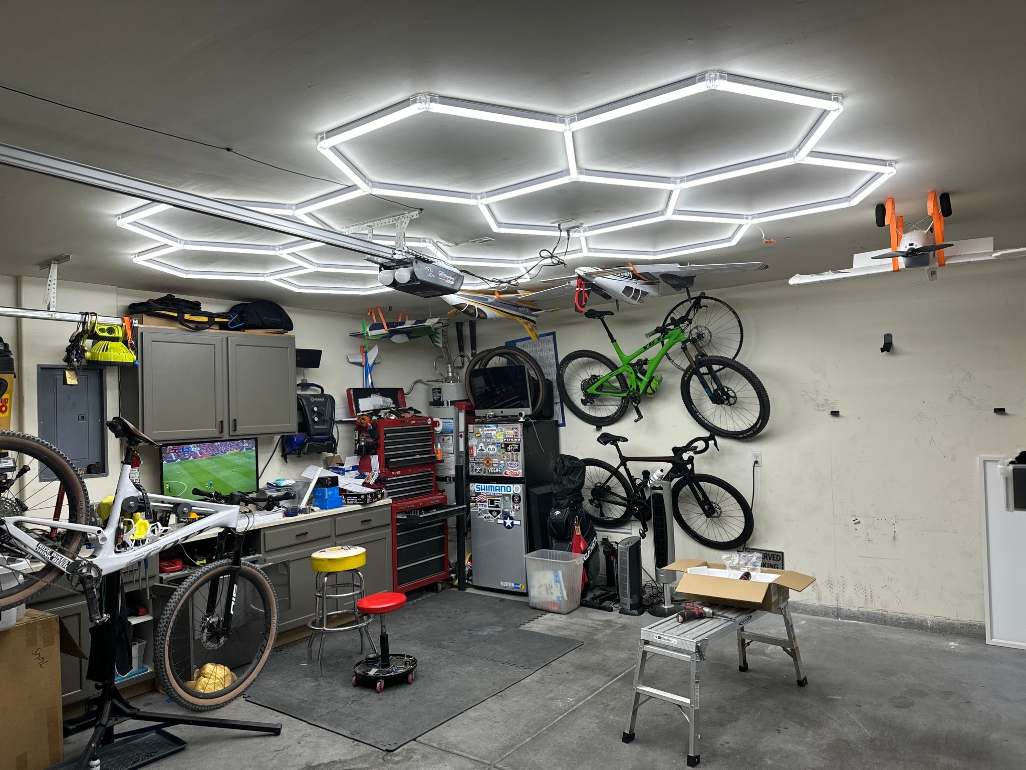 	Garage bike repair area with hexagonal LED ceiling lights and several bikes mounted on the wall