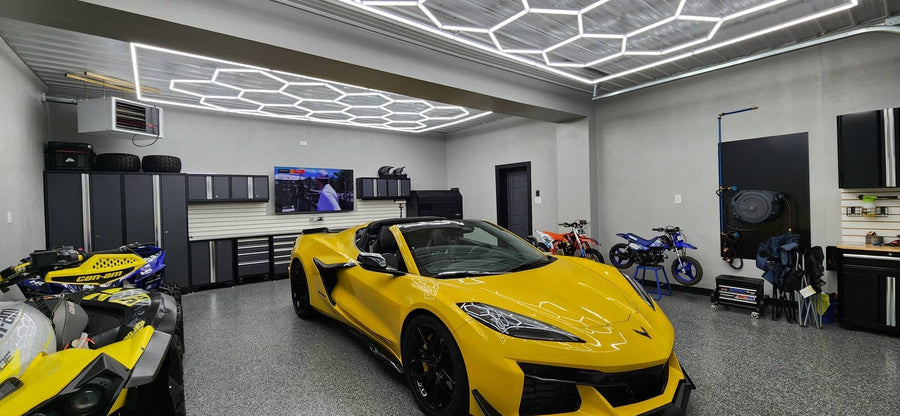Hexagon LED garage ceiling lights lighting up a showroom garage featuring a yellow Corvette, motorcycles, and ATVs.