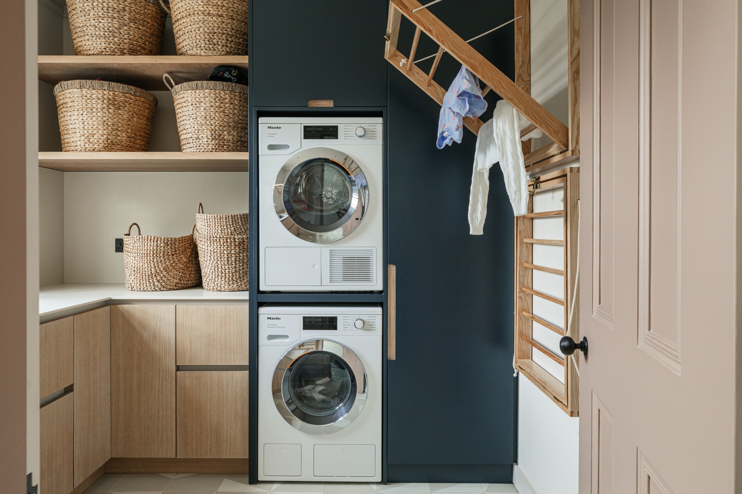 Laundry room with stacked washer and dryer, wicker storage baskets, and a wall-mounted drying rack