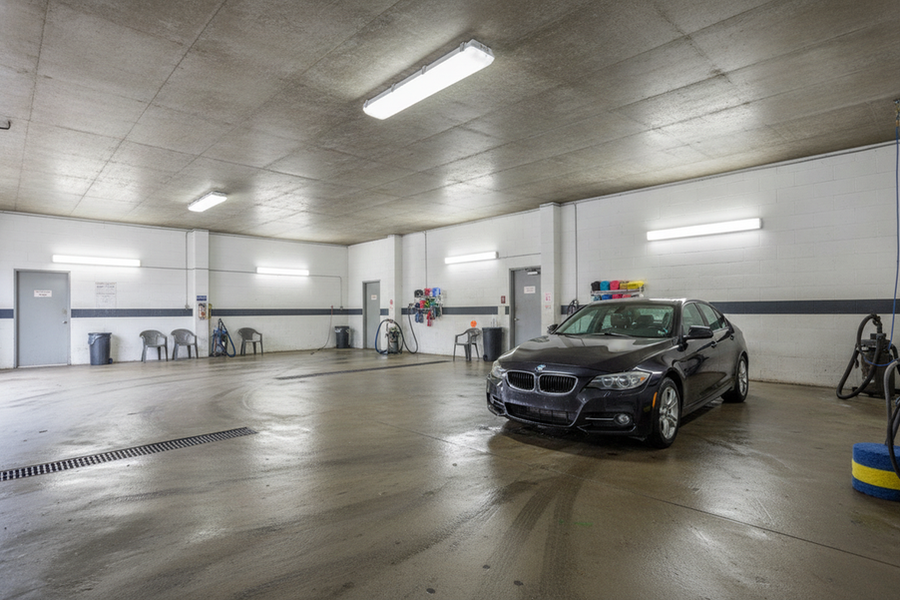 A vapor-tight LED fixture illuminating a small car wash with separate entry, waiting, dry-service, and wash-adjacent areas.