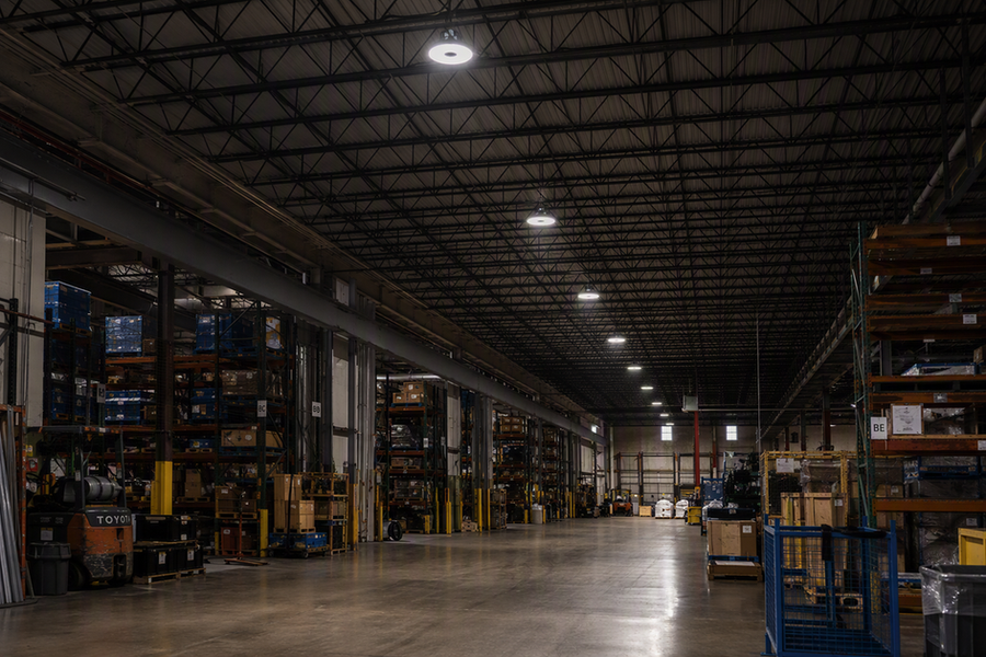 LED high bay fixtures illuminating a spacious industrial warehouse from the ceiling