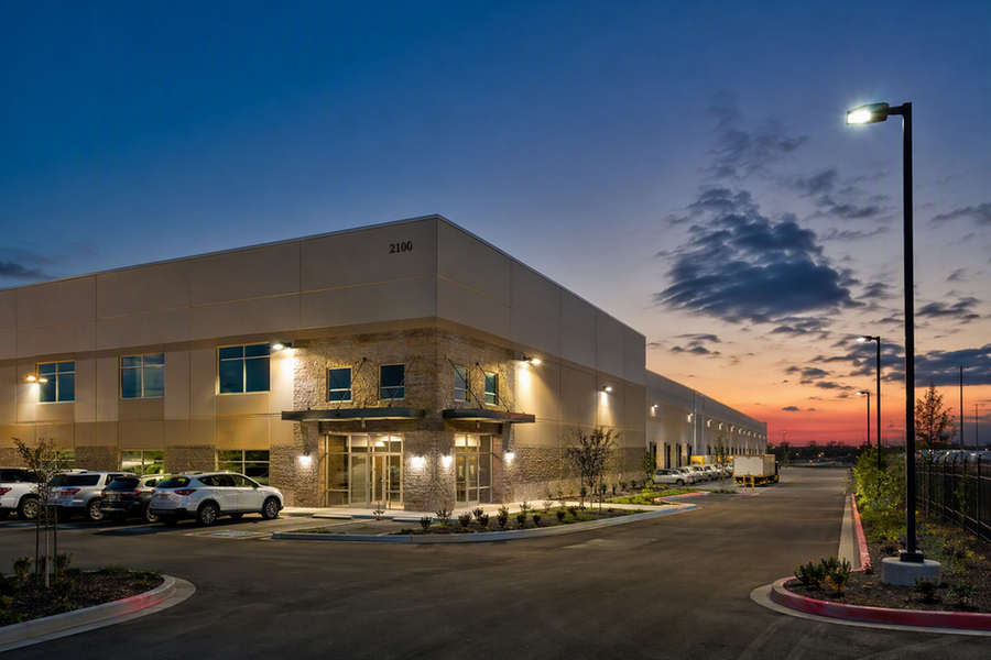 Commercial building exterior at dusk with entrance, wall, parking, and perimeter lighting operating across distinct areas