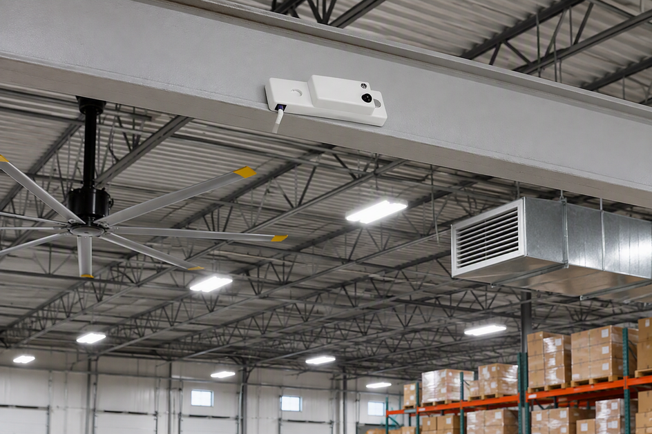 Microwave motion sensor presented in a warehouse lighting context with an overhead fan and HVAC vent visible in the background.