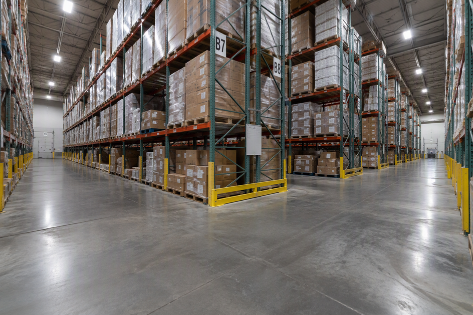 Warehouse cross aisle meeting two rack aisles beneath high-bay lighting; the intersection and aisle ends are visible for location-by-location review.