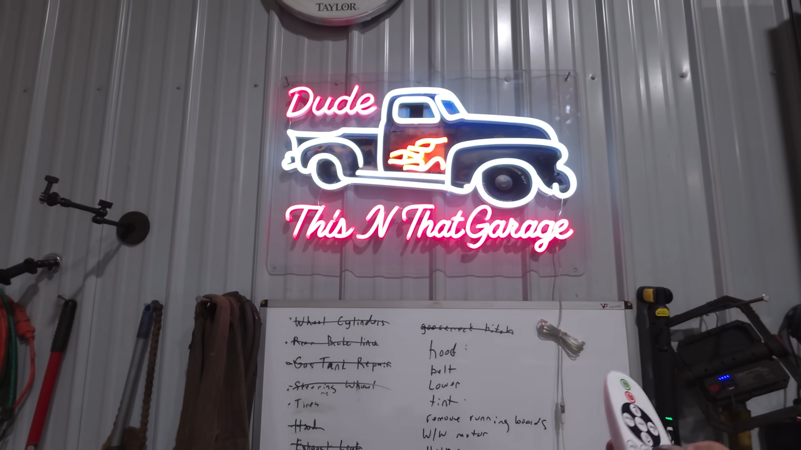 A custom neon garage sign displayed above a workshop whiteboard