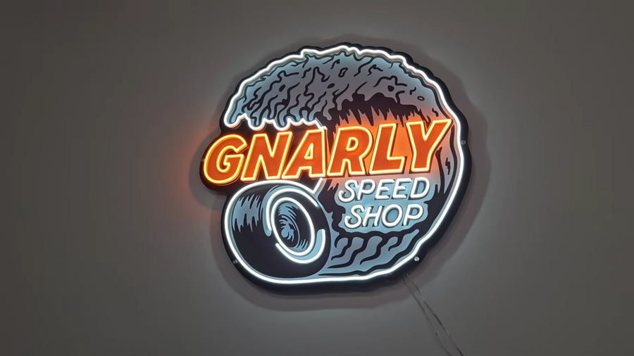 A custom pink and white neon logo sign mounted in a garage