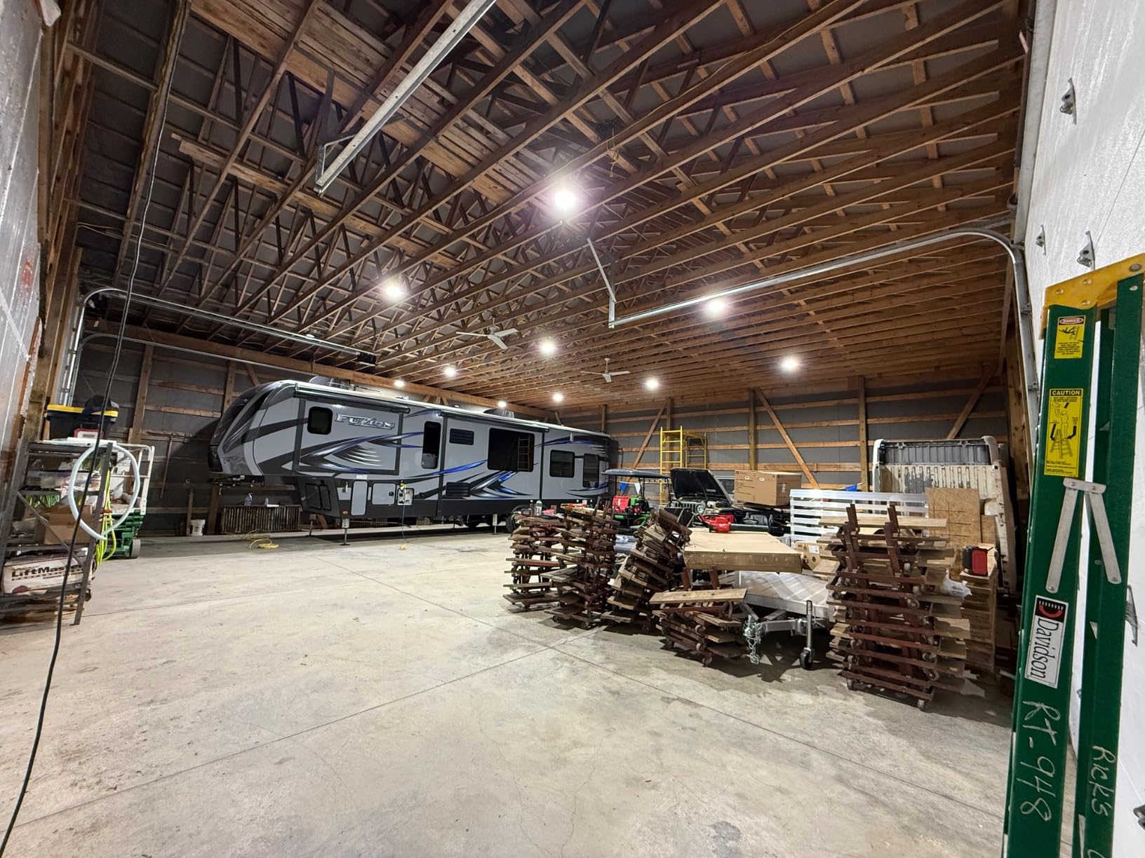 High-lumen LED High Bay shop lights illuminating a pole-barn garage workshop with RV and stacked materials